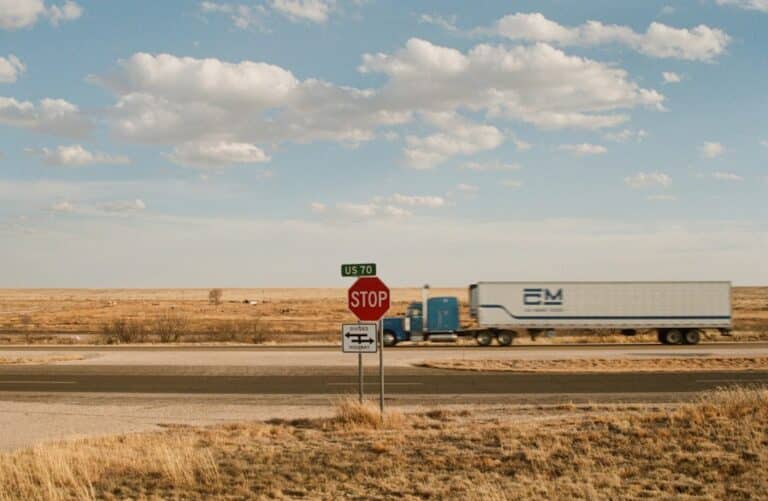 Tractor-trailer traveling through open farmland