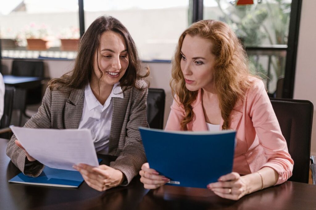 Two office colleagues review documents at a table.