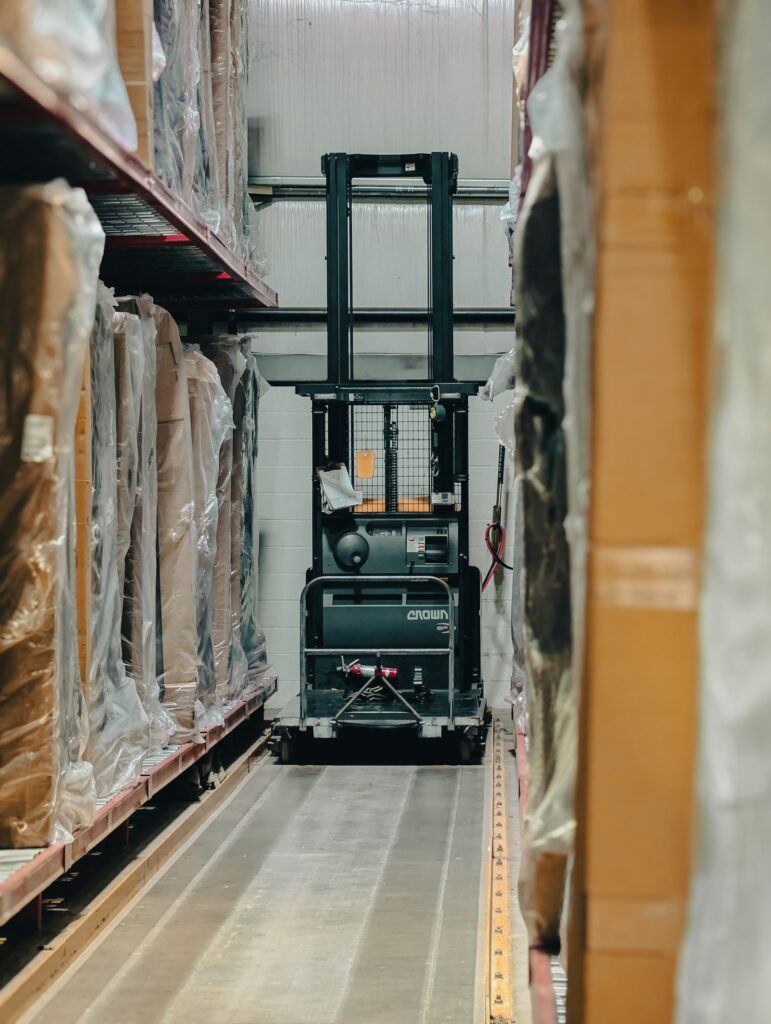 Warehouse aisle with pallet racks, boxed inventory and a forklift