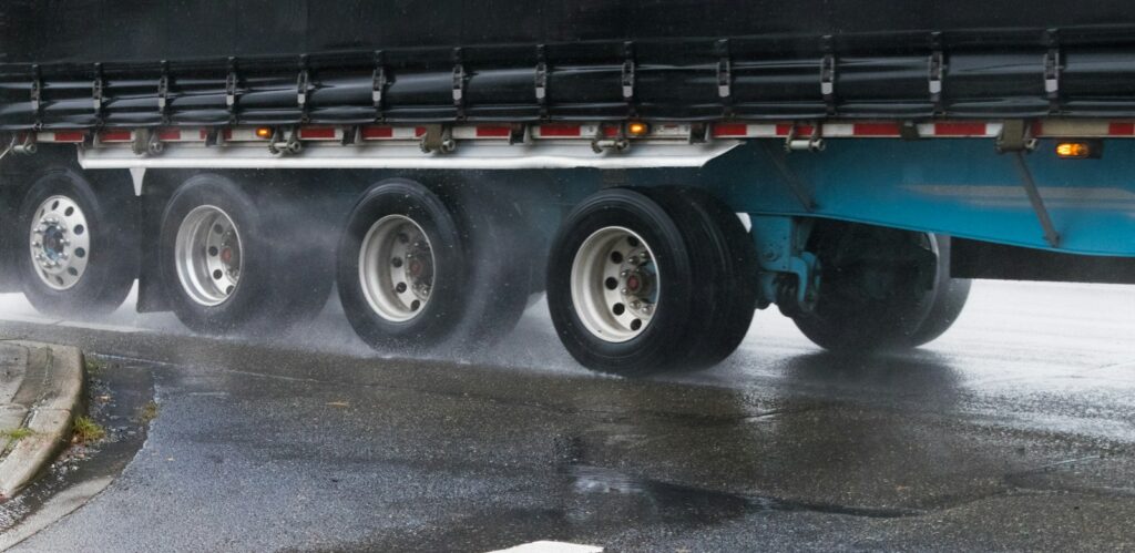 Semi truck hauling a flatbed trailer on a wet road in Tacoma