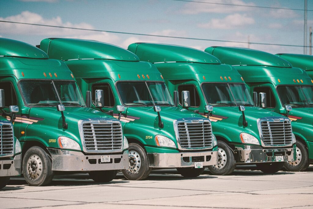 Green conventional semi-trucks parked side by side.