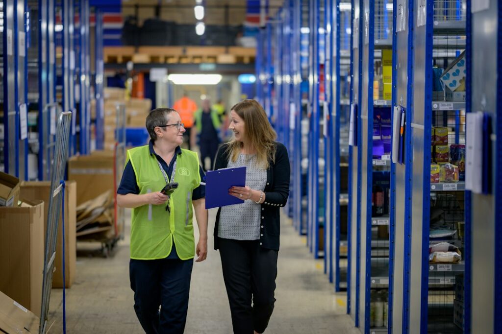 Two logistics professionals reviewing a clipboard in a warehouse aisle